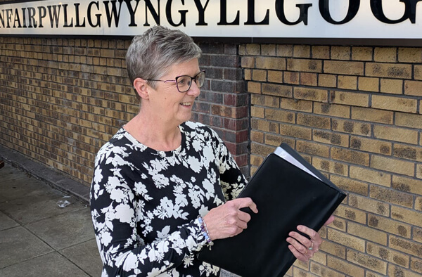Louise Rooney, a funeral celebrant in Anglesey, holding a ceremony folder in Llanfairpwll